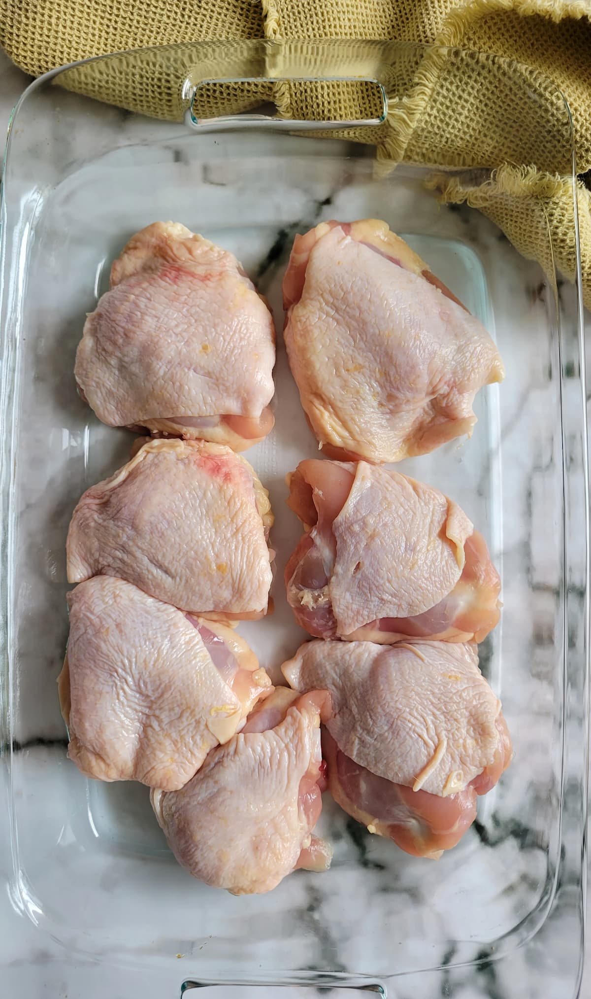 7 raw chicken thighs in a casserole dish