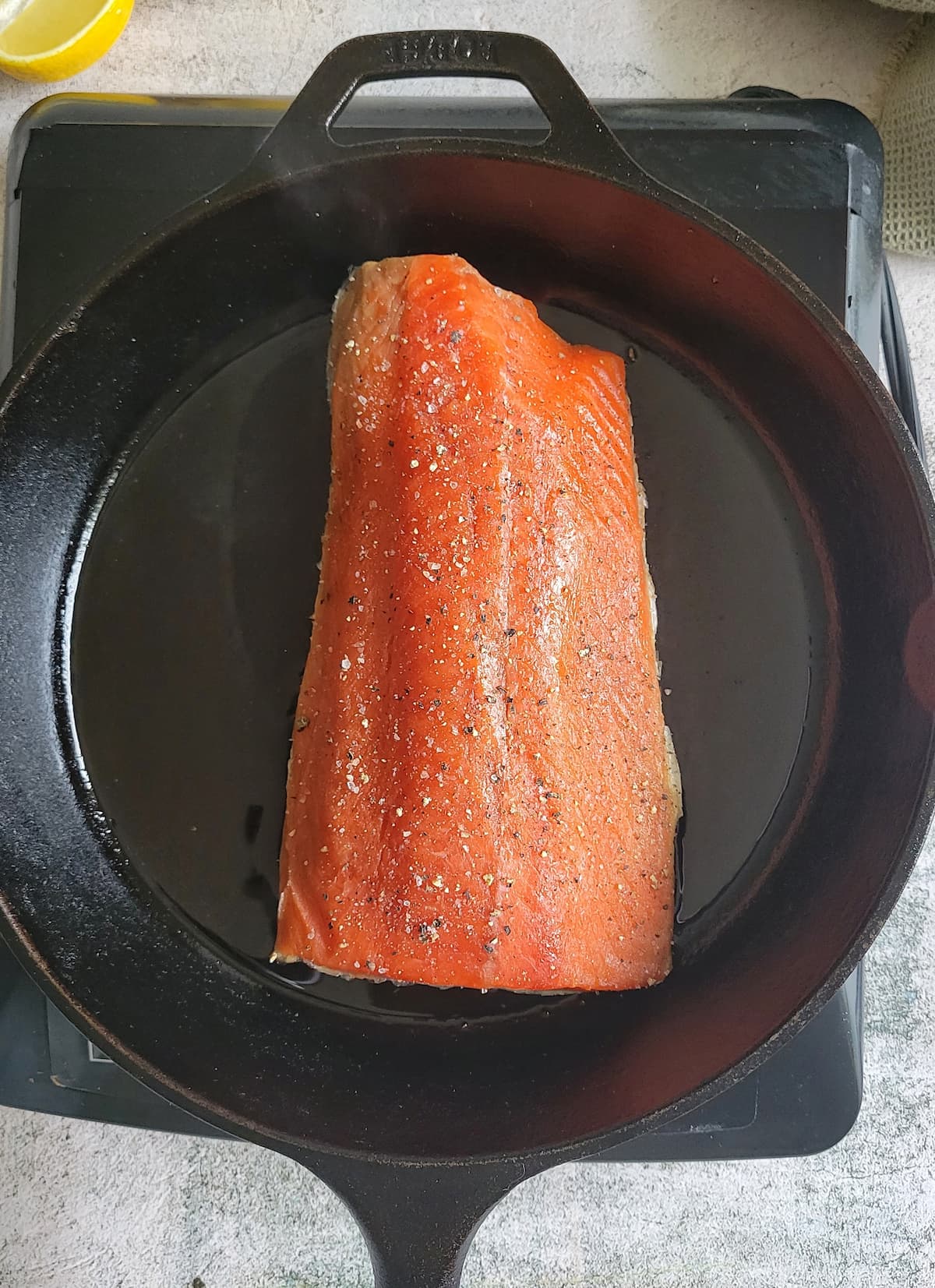 raw salmon seasoned with salt and pepper in a cast iron skillet