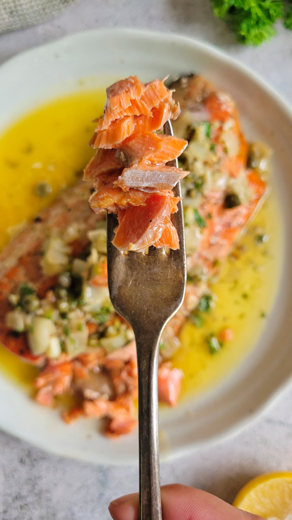 flakes of salmon on a fork over a plate with the rest of it