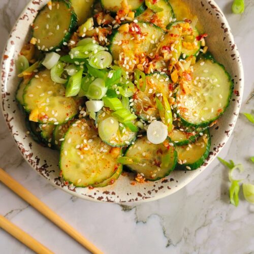 bowl of cucumbers with green onions, sesame seeds and a spicy sauce