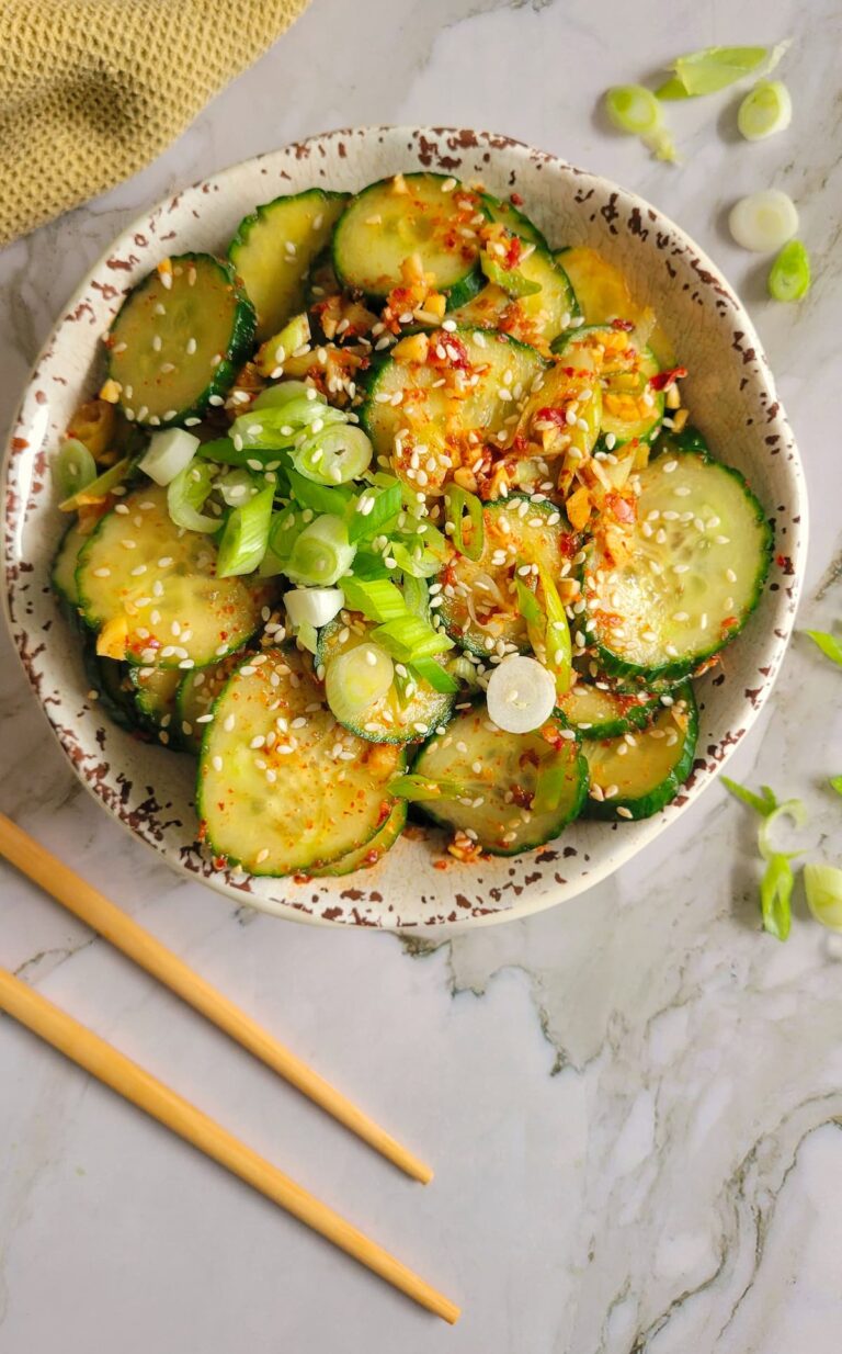 bowl of cucumbers with green onions, sesame seeds and a spicy sauce
