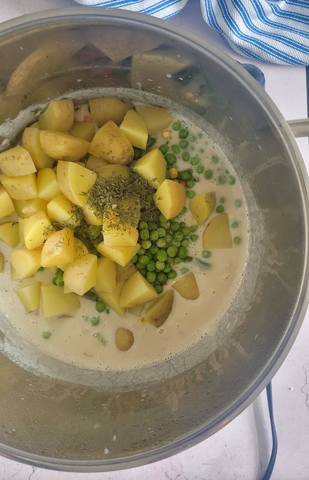 chunks of potatoes, peas and spices in a pot of cream