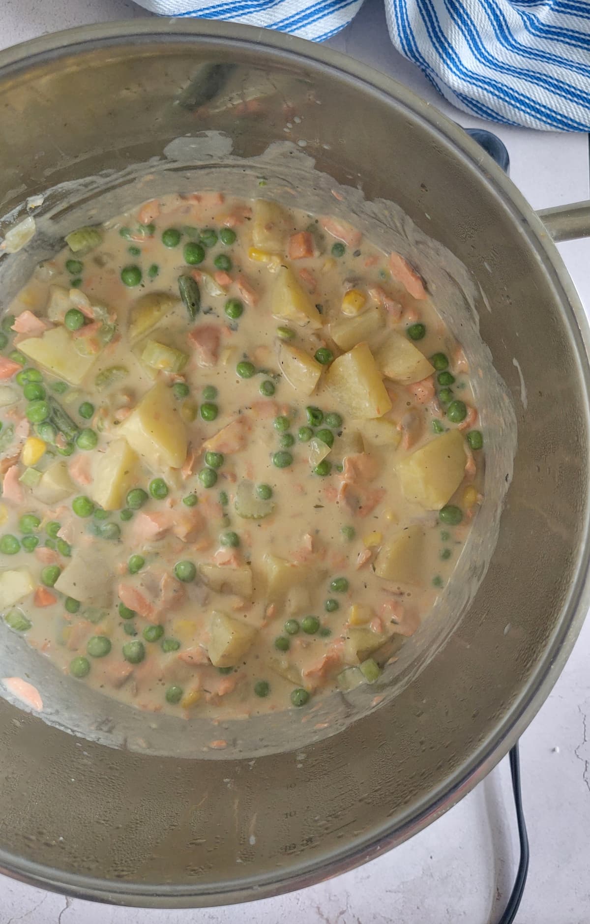 salmon chowder with peas, potatoes and cream in a pot