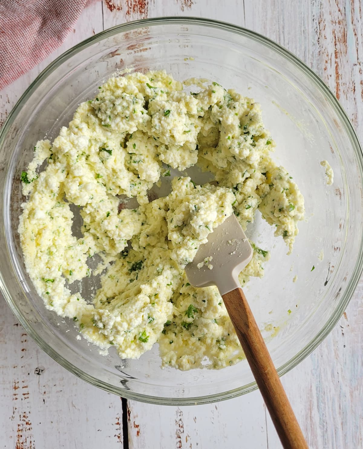 ricotta and spices mixed in a bowl with a rubber spatula