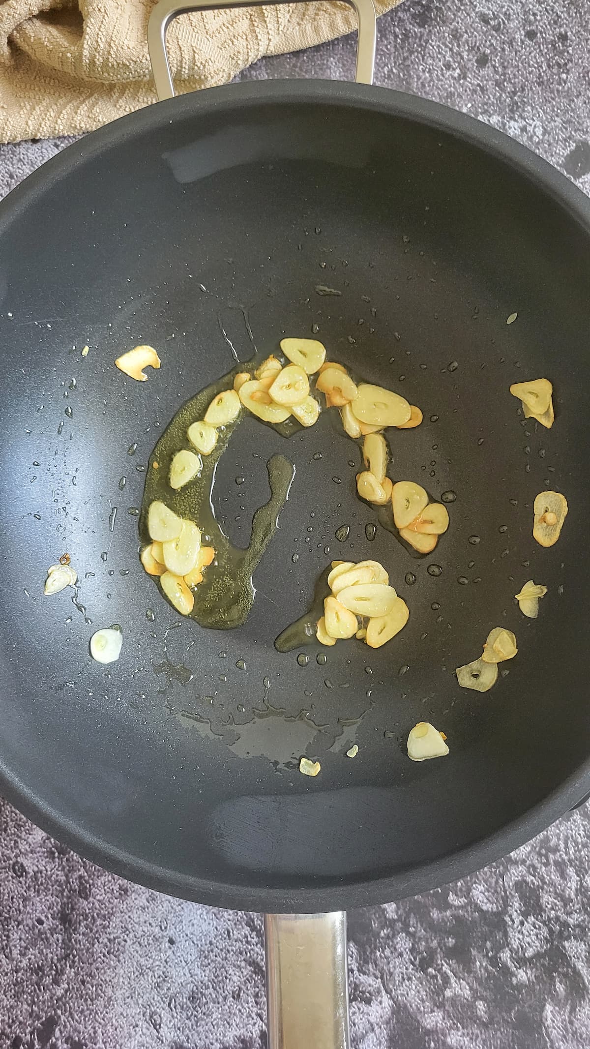 sliced garlic cooking in oil in a wok