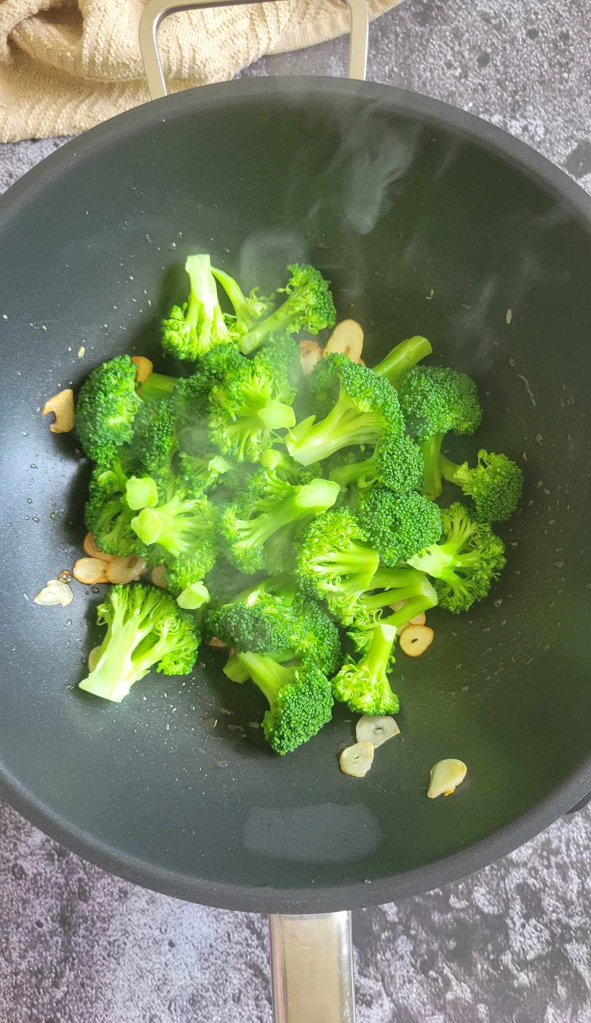 broccoli florets and sliced garlic cooking in a wok