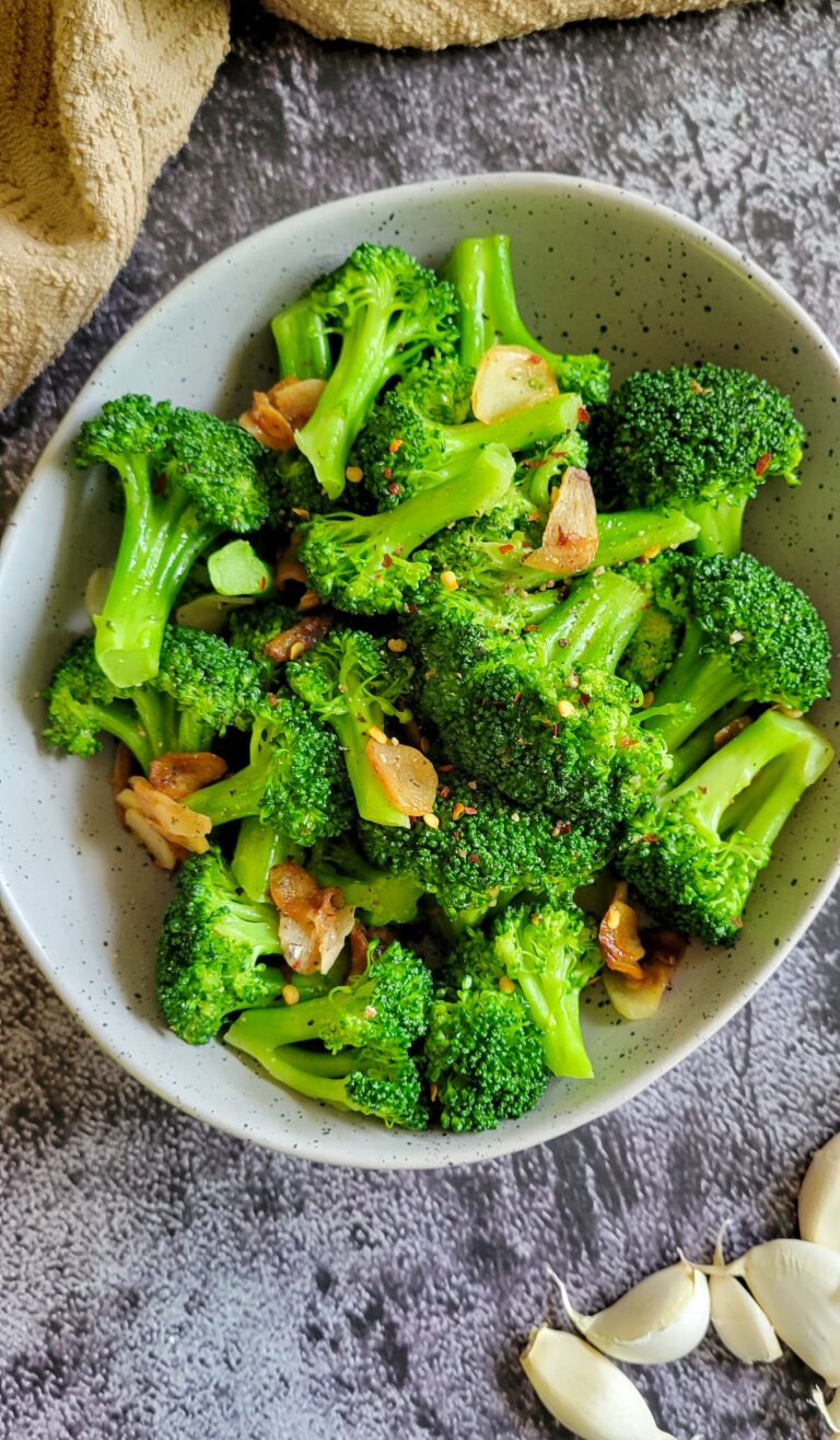 garlic broccoli in a bowl, unpeeled garlic cloves on the side