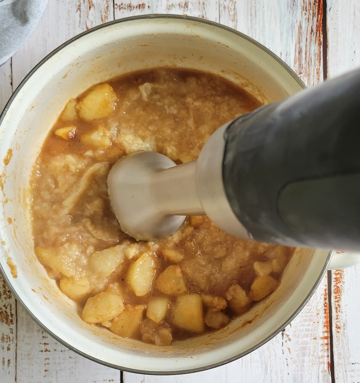 immersion blender in a pot with half pear chunks and half pureed