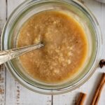 pear puree in a jar with a spoon, cinnamon sticks next to the jar