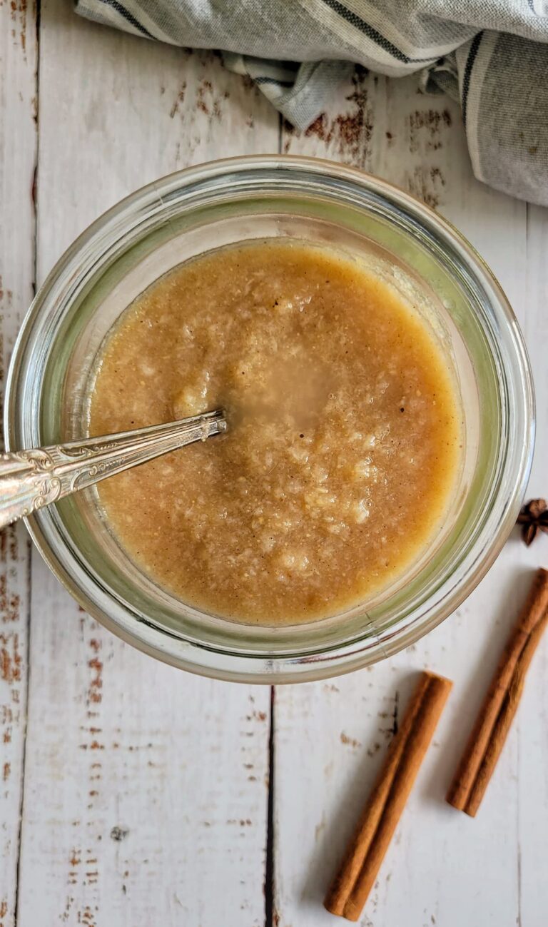 pear puree in a jar with a spoon, cinnamon sticks next to the jar