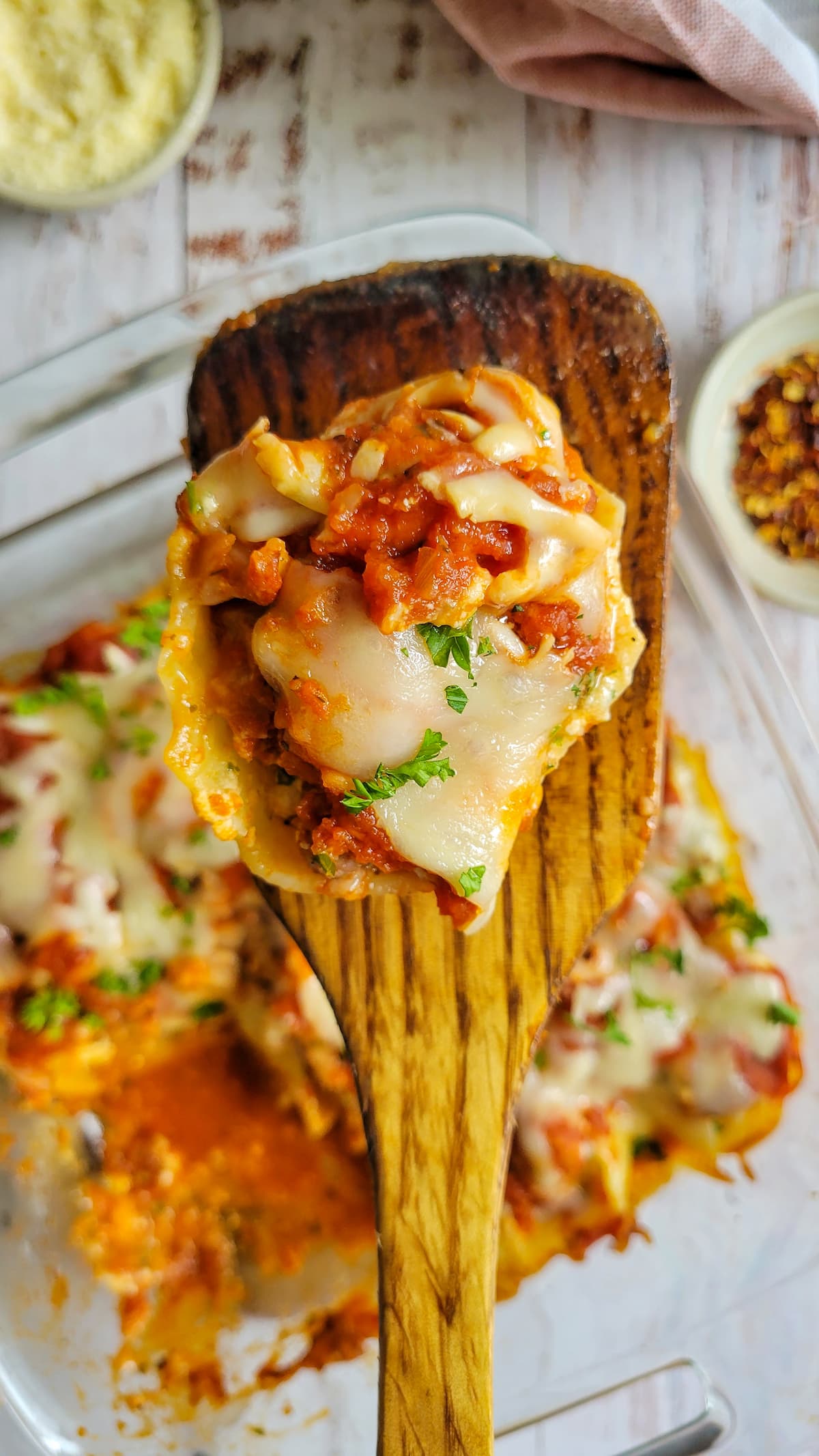 wooden spatula with a stuffed pasta shell on it over a dish with the rest of them