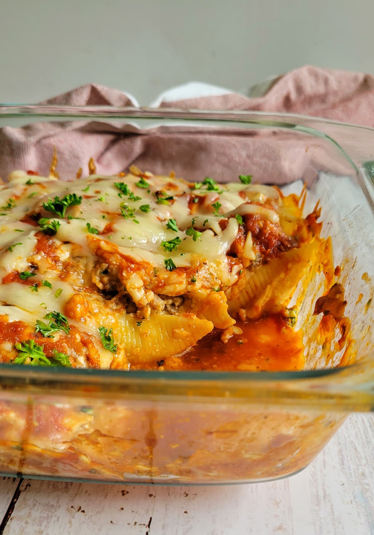 stuffed pasta shells with mozzarella, tomato sauce and fresh chopped parsley in a baking dish