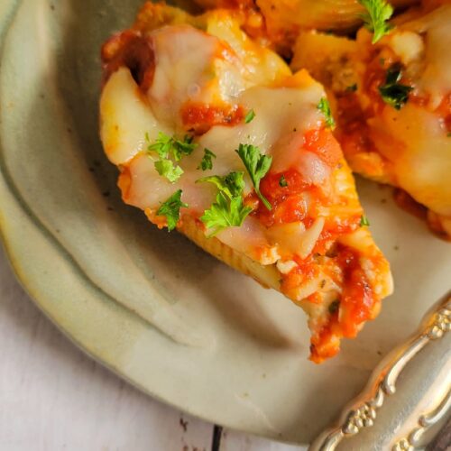 close up of a stuffed pasta shell with chopped parsley and mozzarella