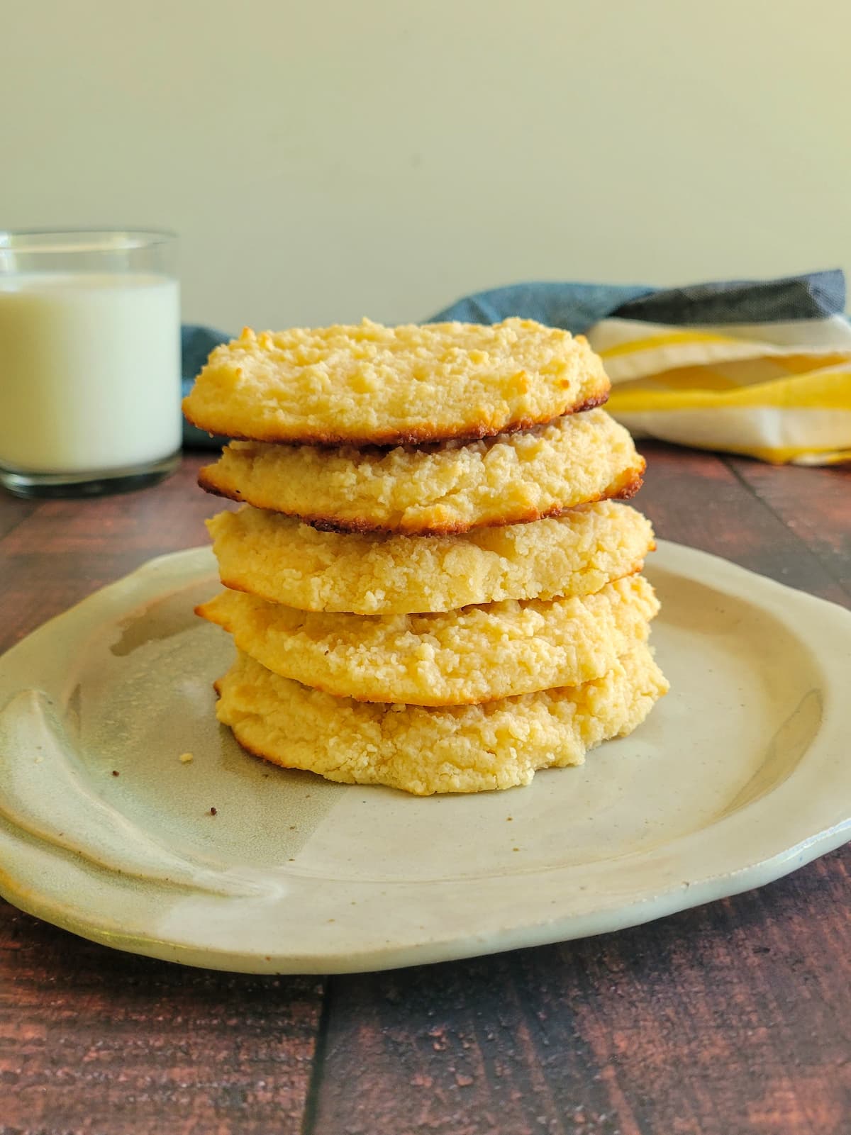 5 cookies stacked on a plate, glass of milk in the background