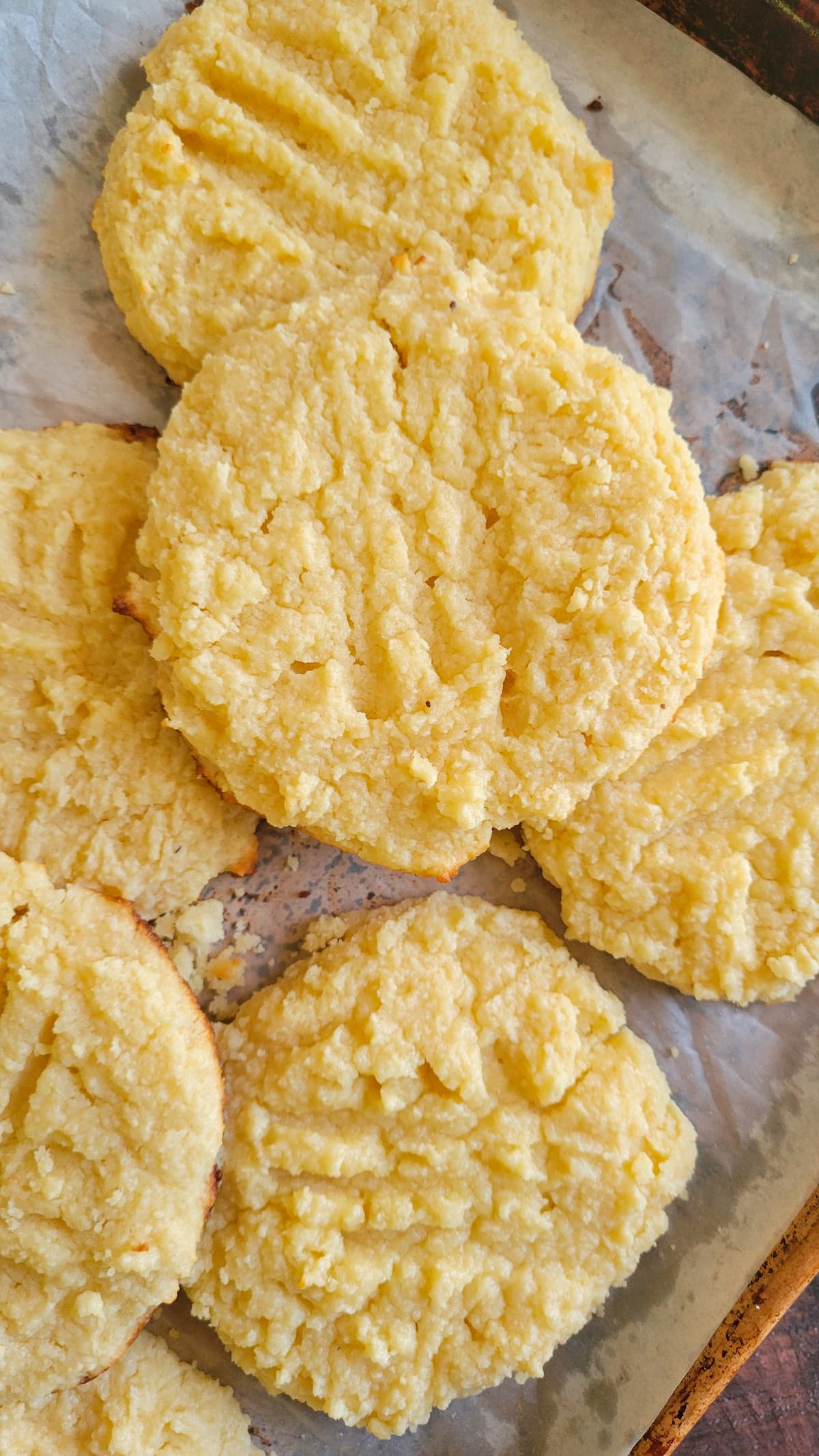 7 large yellow-ish cookies on a parchment lined baking sheet