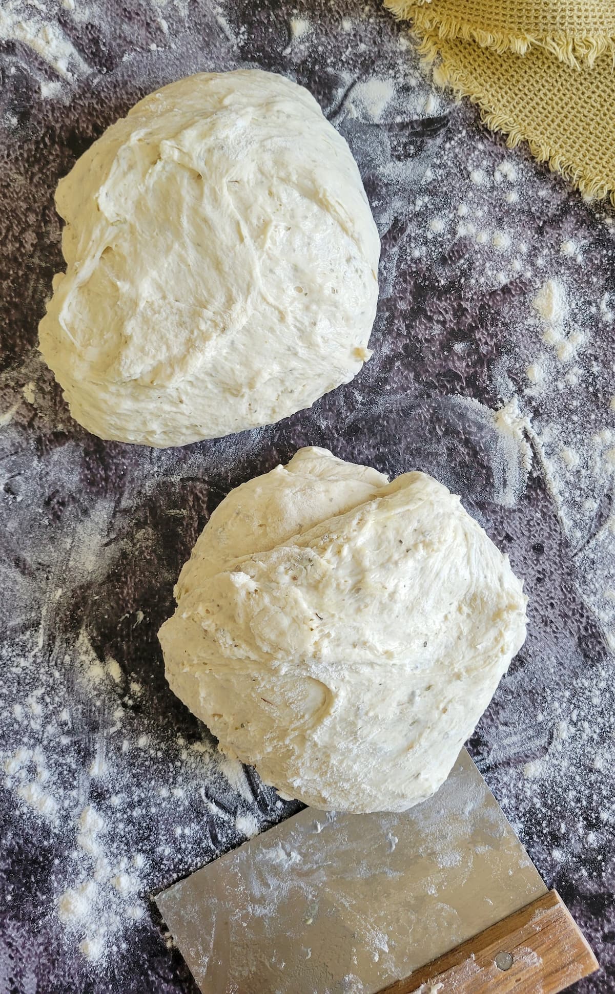 two raw balls of dough on a floured surface with a dough card