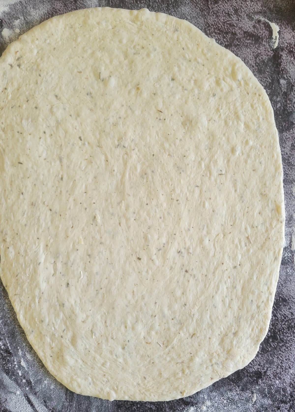 circular raw pizza dough on a floured surface