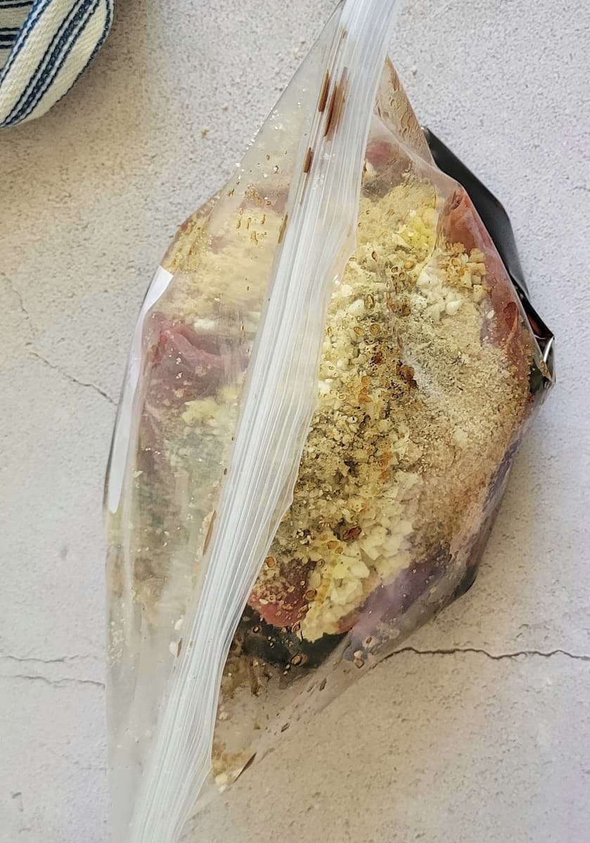 spices and soy sauce with raw meat in a sealed ziploc bag