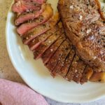 two steaks on a plate, one sliced and pink, other whole