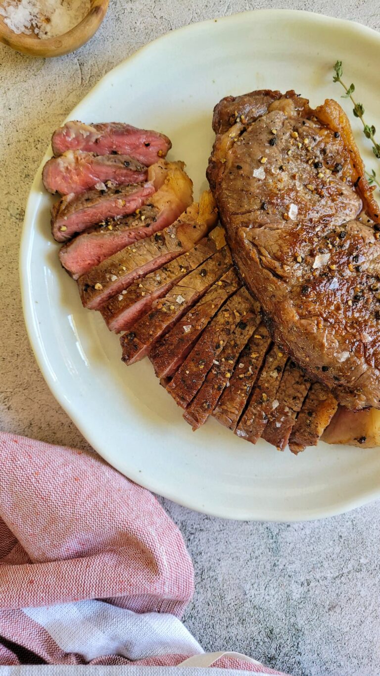 two steaks on a plate, one sliced and pink, other whole