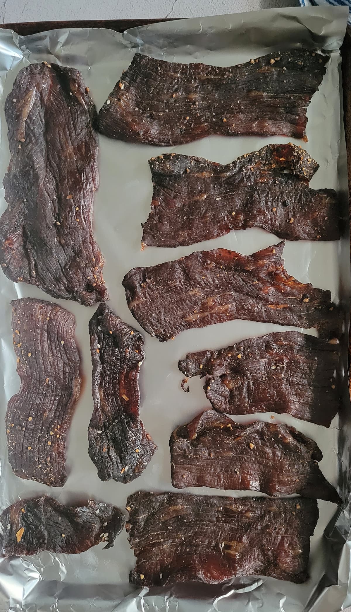 slices of beef jerky on an aluminum foil lined baking sheet