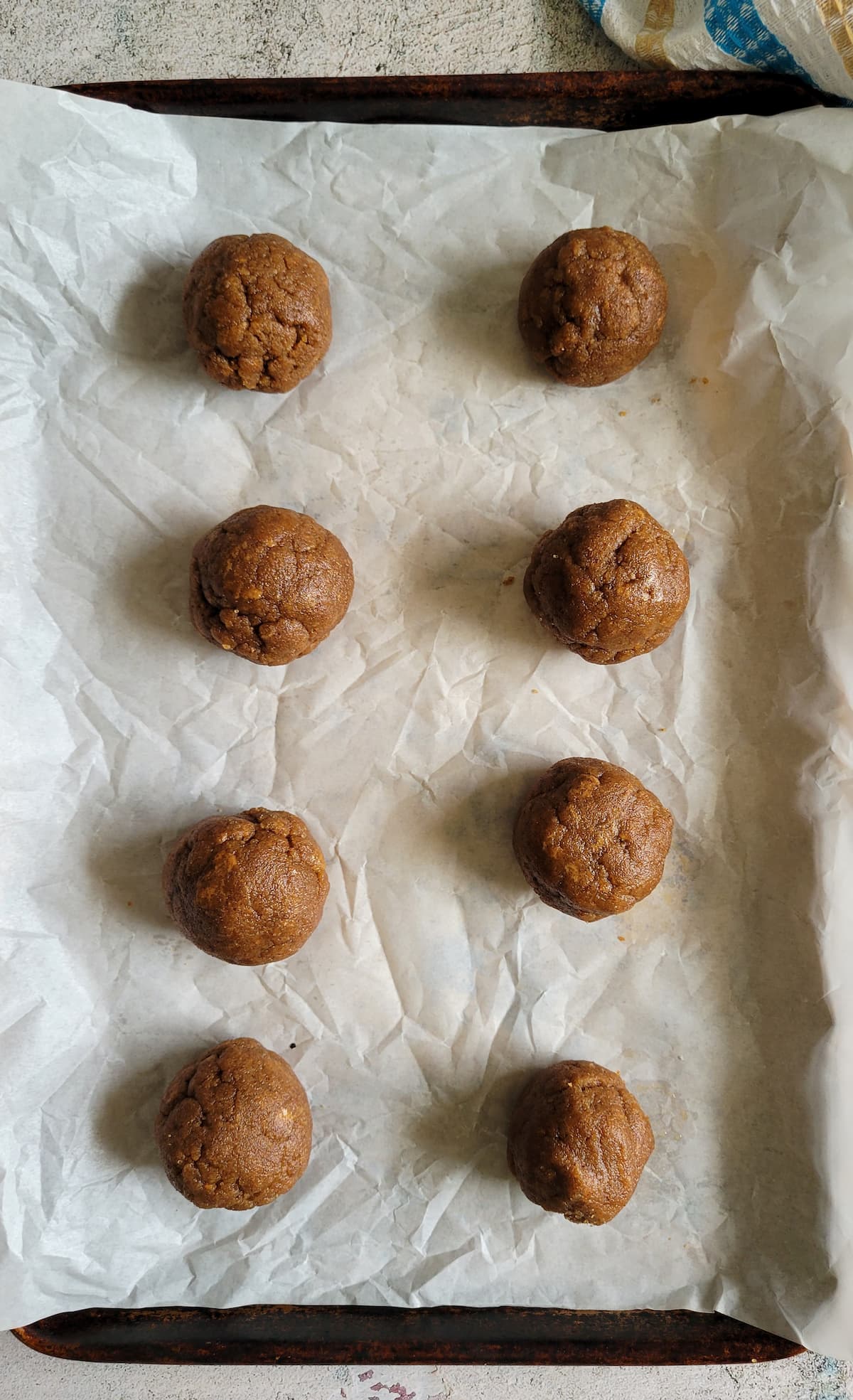 8 balls of cookie dough on a parchment lined baking sheet