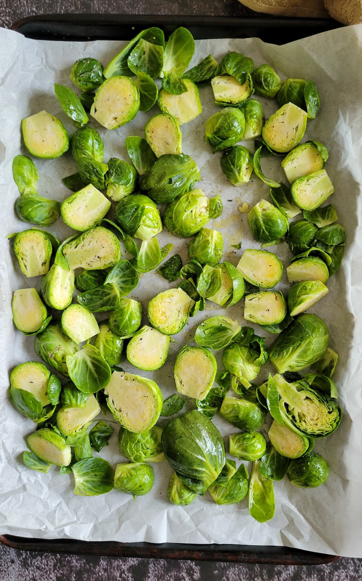 halved and trimmed raw brussels sprouts on a parchment lined baking sheet