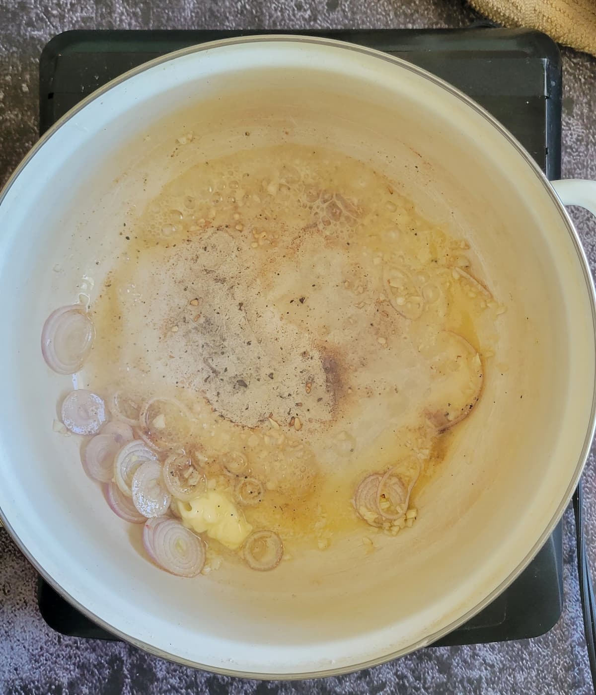 shallots and garlic cooking in butter in a pot on a burner