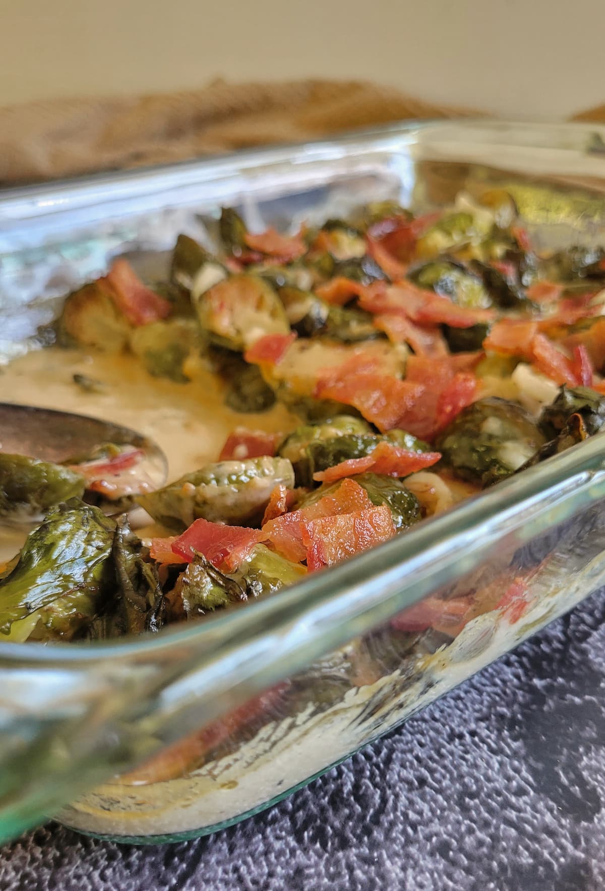side view of creamy brussels sprouts and bacon in a glass baking dish