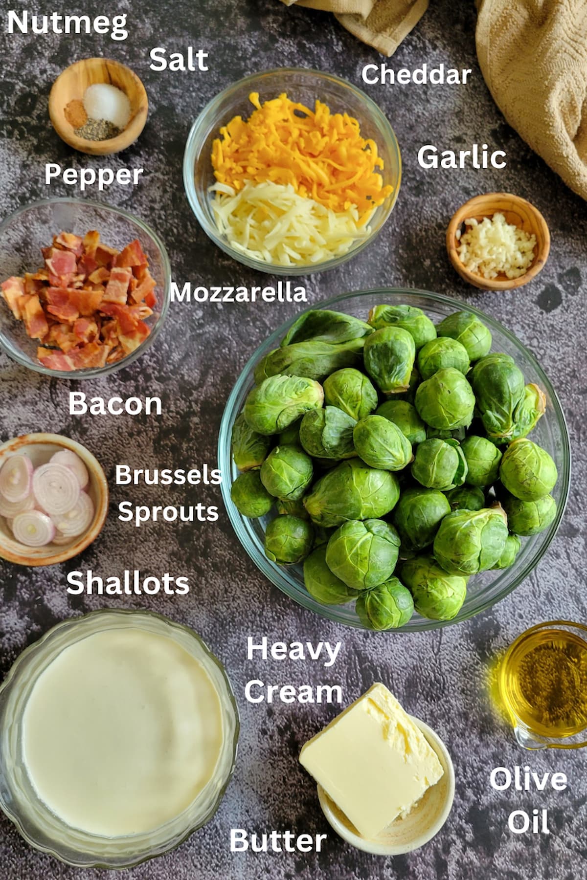 ingredients for brussels sprouts in cream - heavy cream, butter, olive oil, salt, pepper, nutmeg, mozzarella, cheddar, garlic, bacon, shallots, brussels sprouts