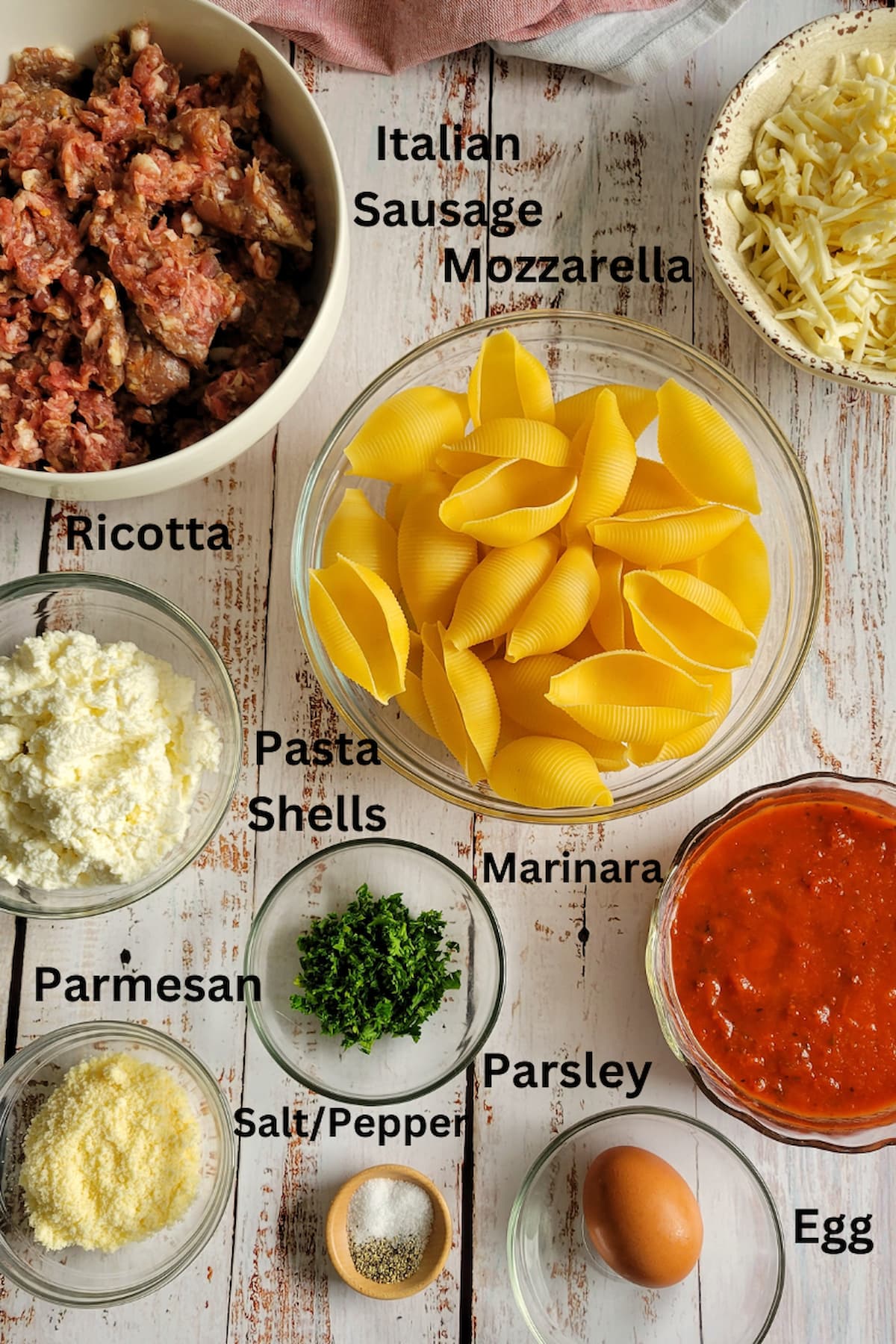 ingredients for recipe for stuffed pasta shells - pasta shells, italian sausage, ricotta, mozzarella, parsley, salt/pepper, marinara, egg, parmesan