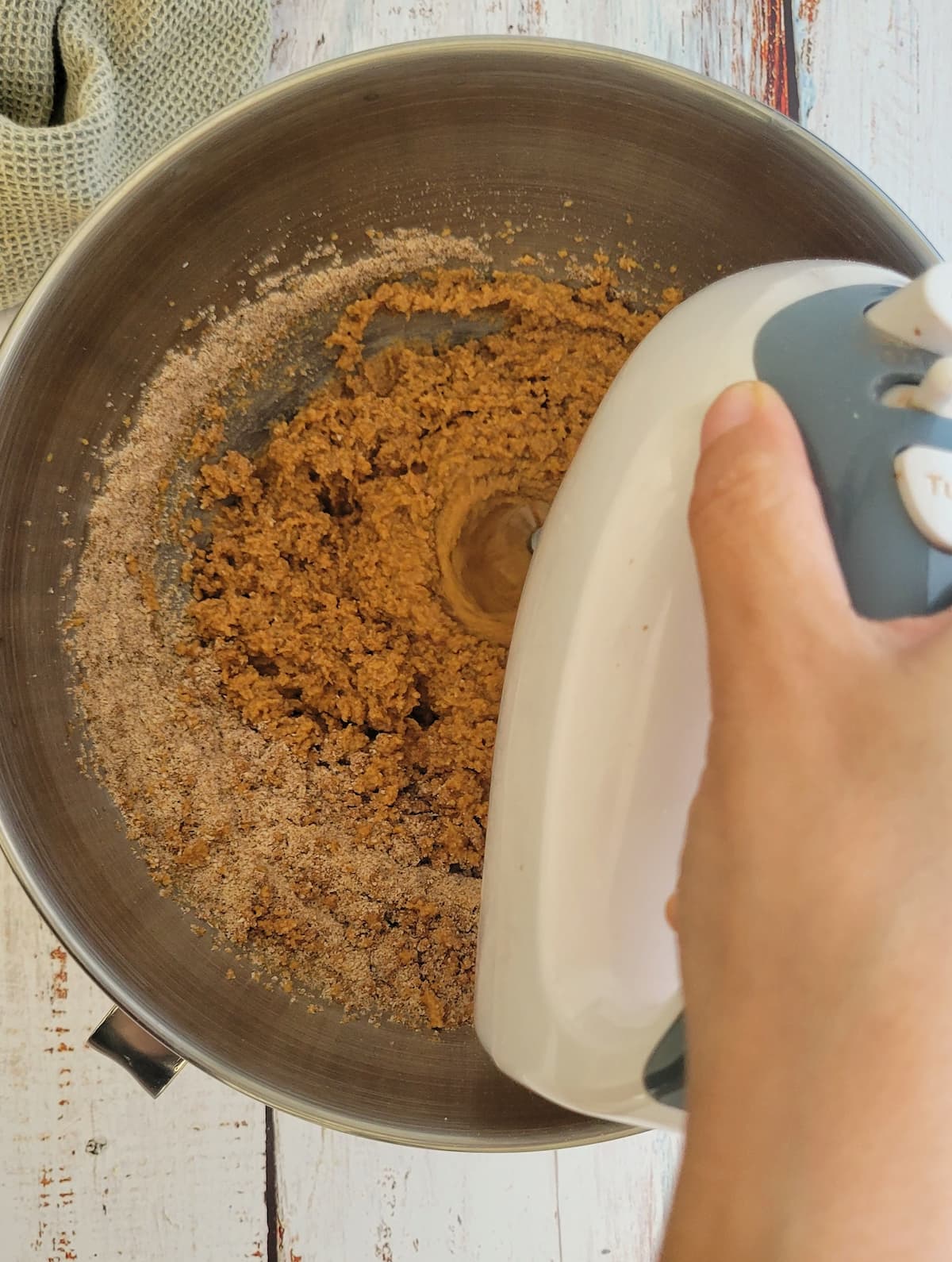hand with an electric mixer mixing batter in a bowl