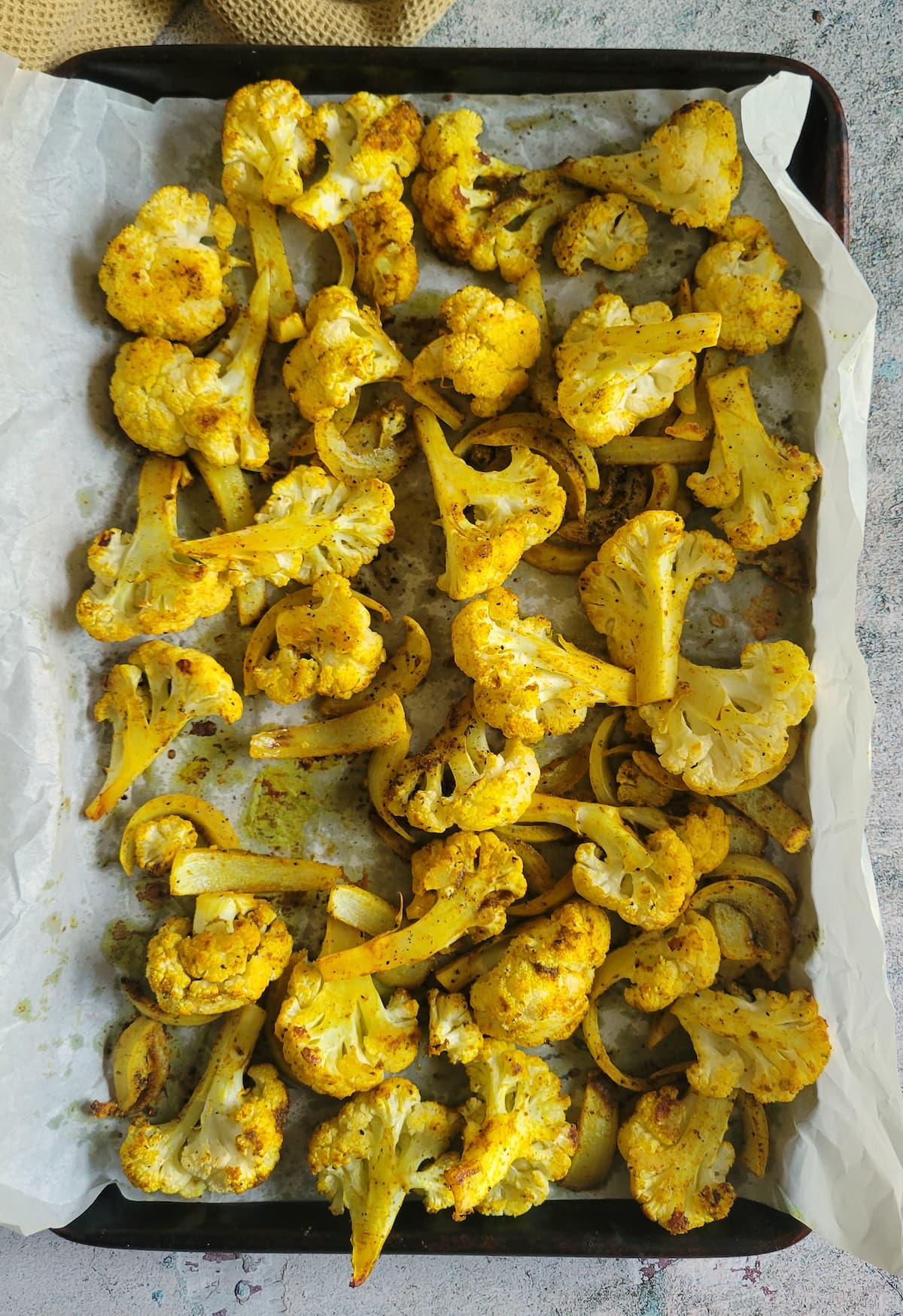 roasted curry cauliflower on a parchment lined baking sheet