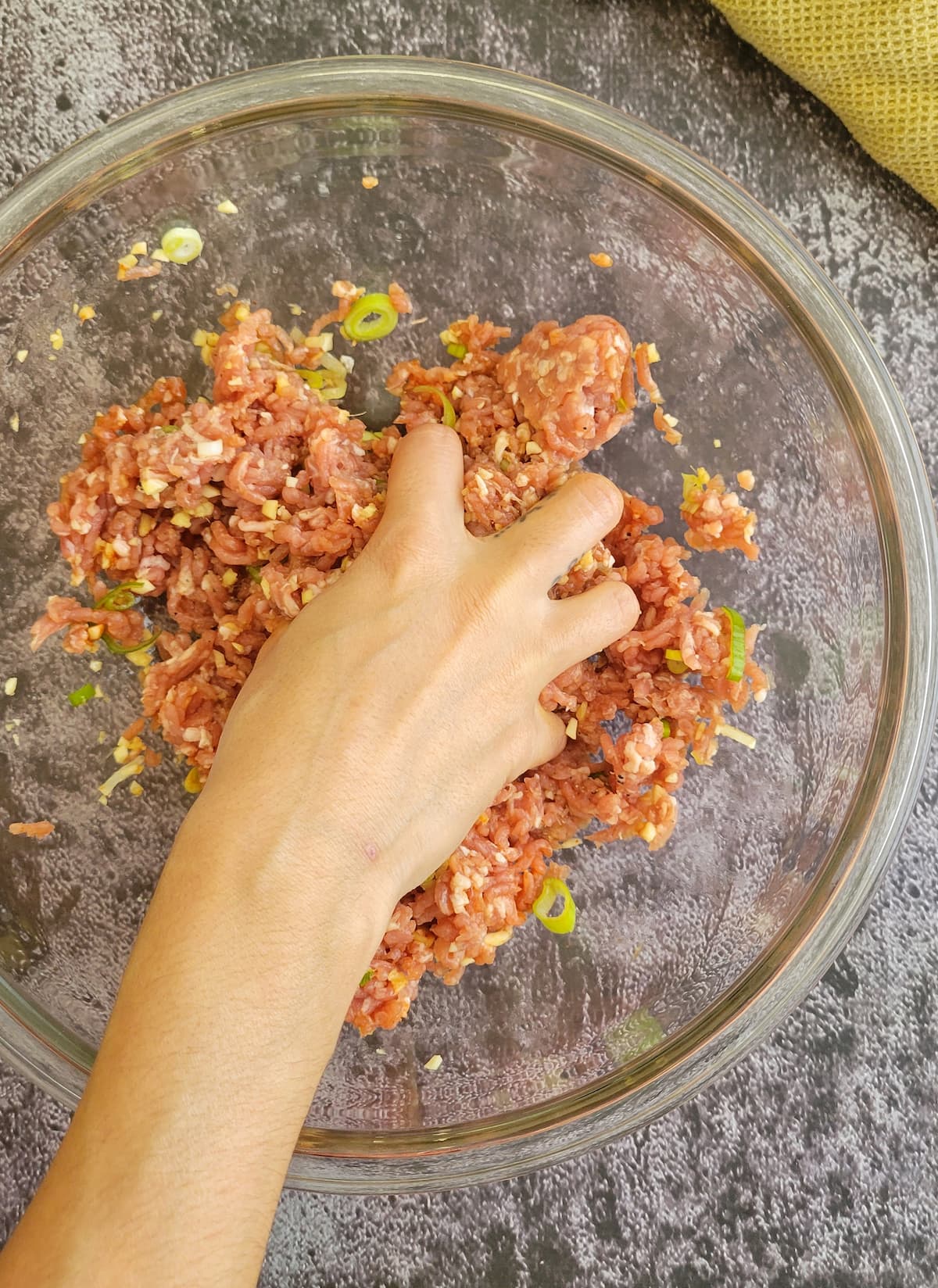hand mixing ground pork in a bowl