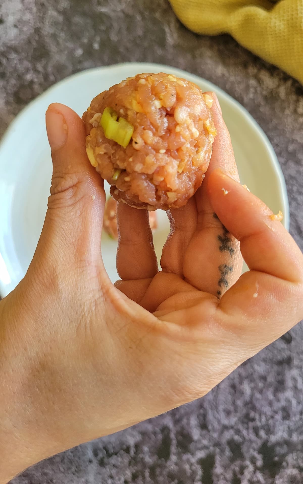 hand holding a raw meatball