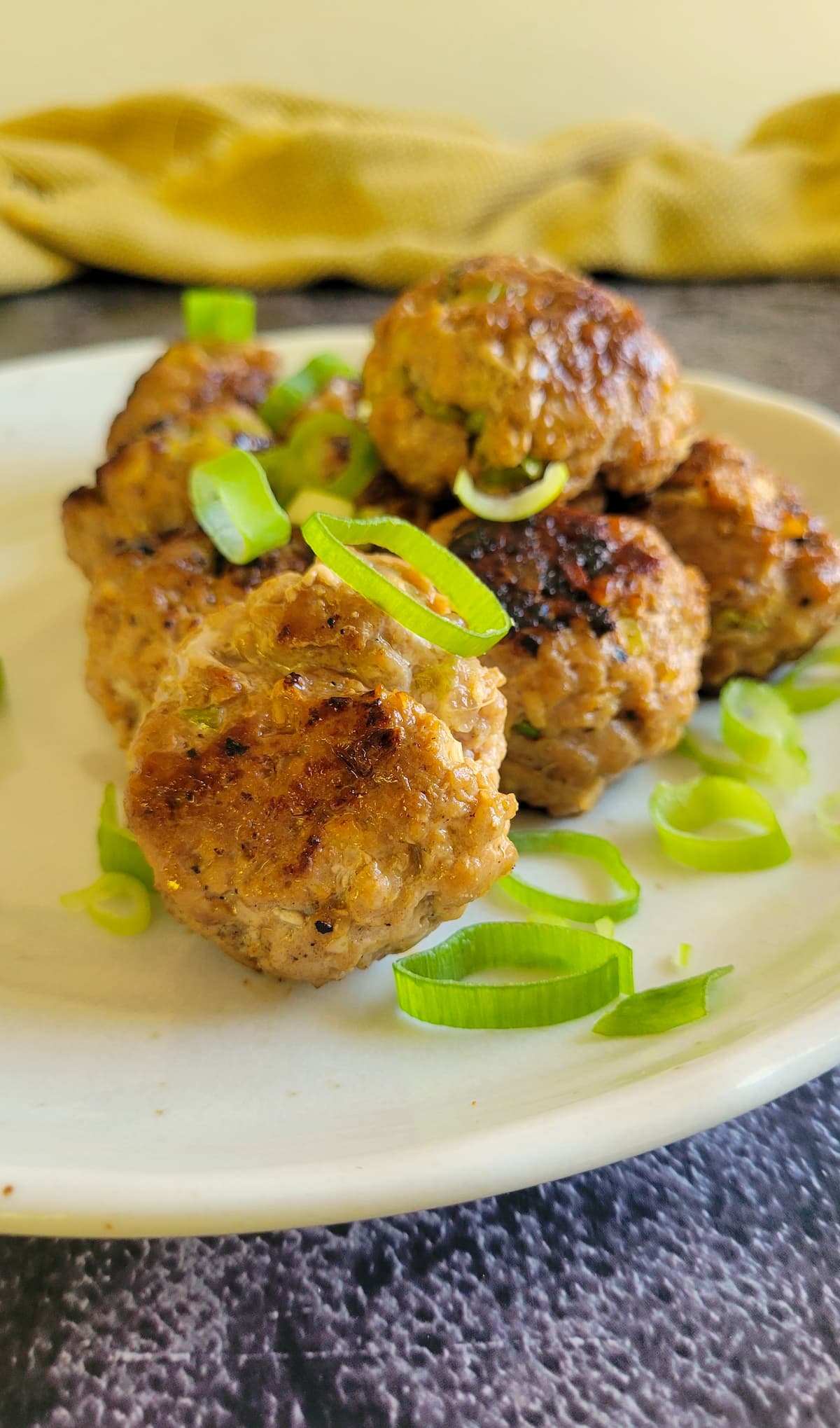 meatballs stacked on a plate garnished with green onions