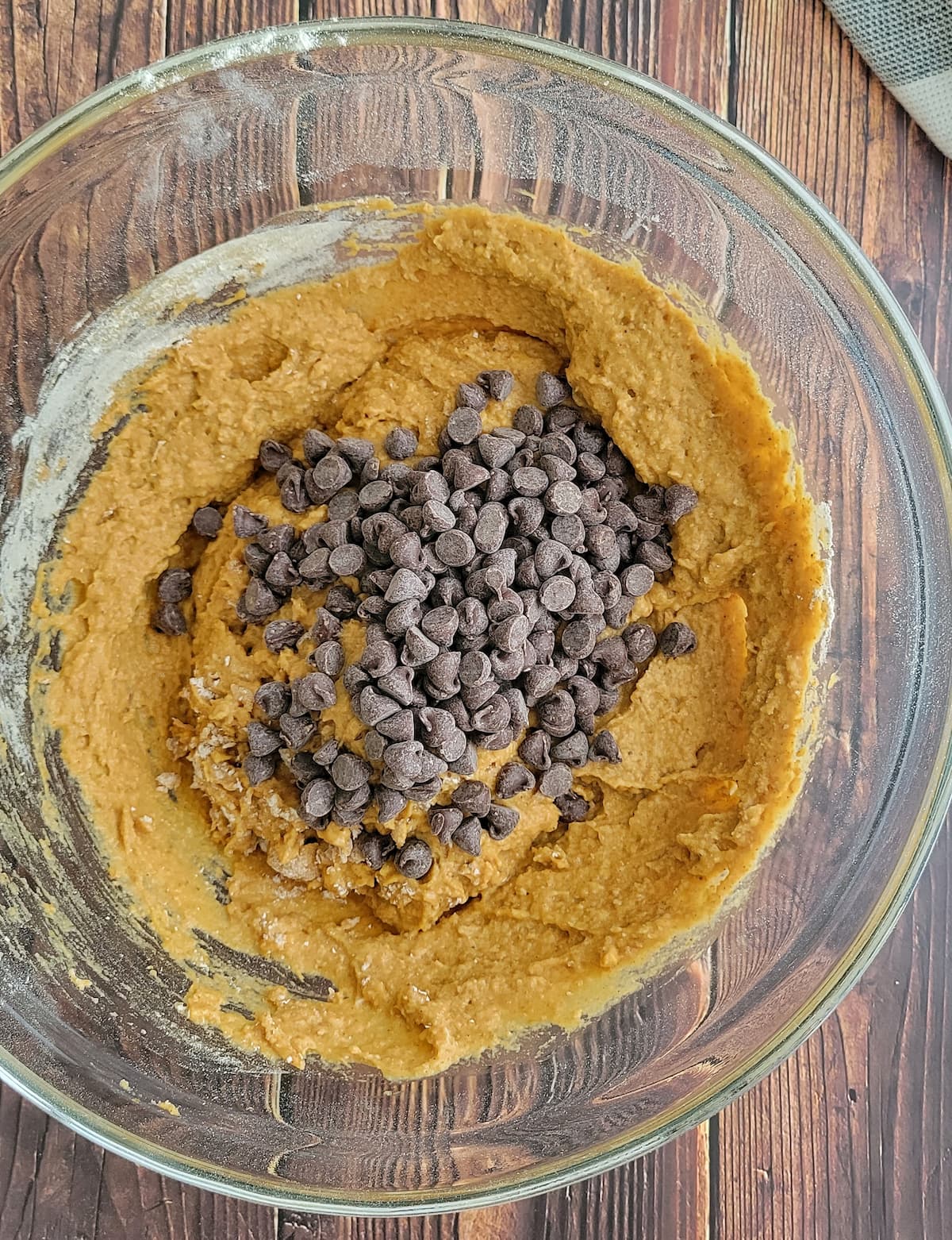 chocolate chips on top of orange batter in a bowl