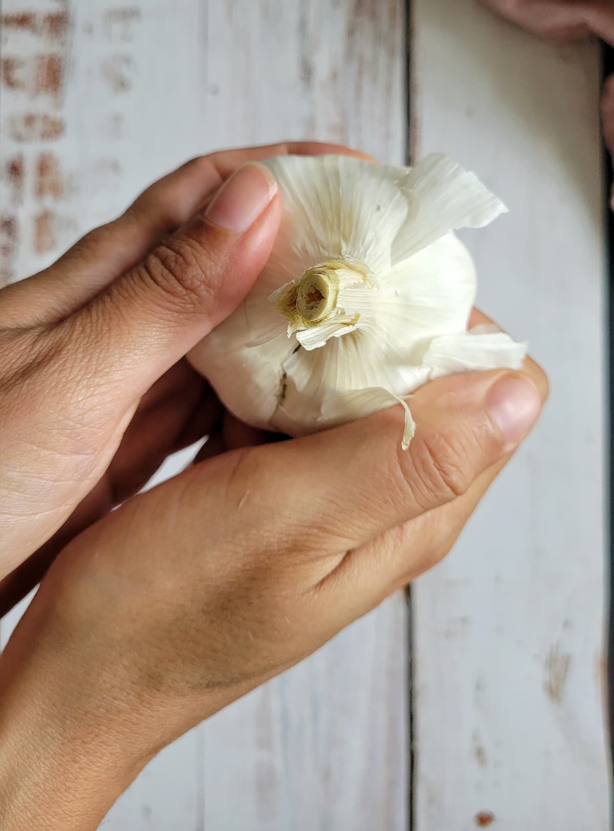 hands peeling back some skin on a head of garlic
