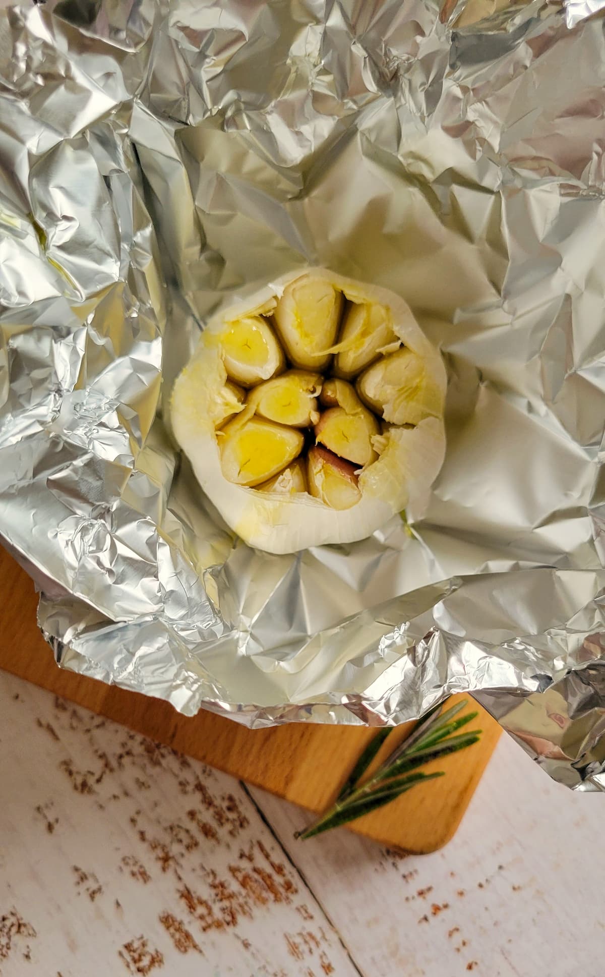 raw sliced garlic bulb in a piece of foil with some olive oil