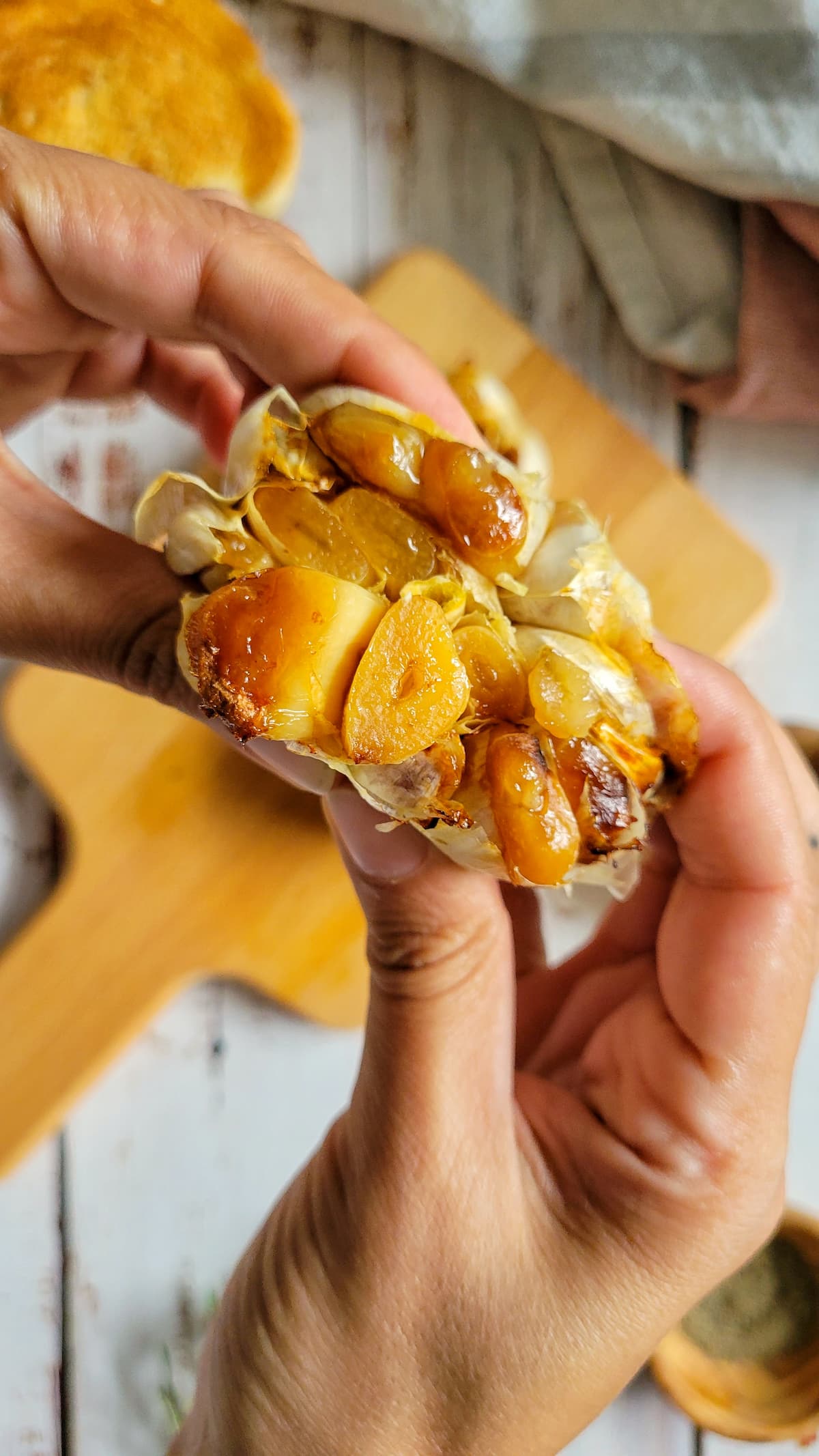 hands squeezing roasted garlic cloves out of a head