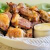 side view of pork riblets in a bowl with sauce