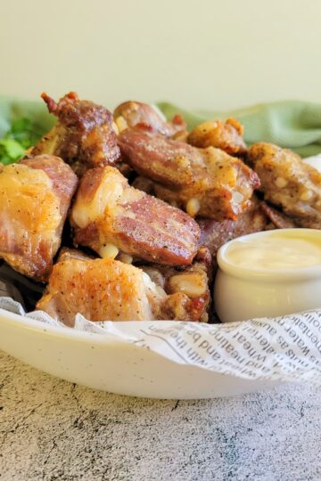side view of pork riblets in a bowl with sauce