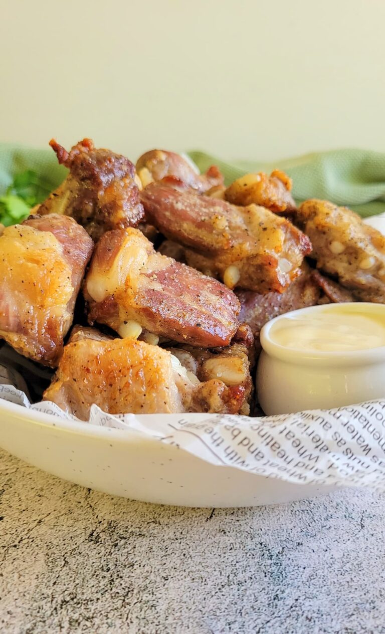 side view of pork riblets in a bowl with sauce