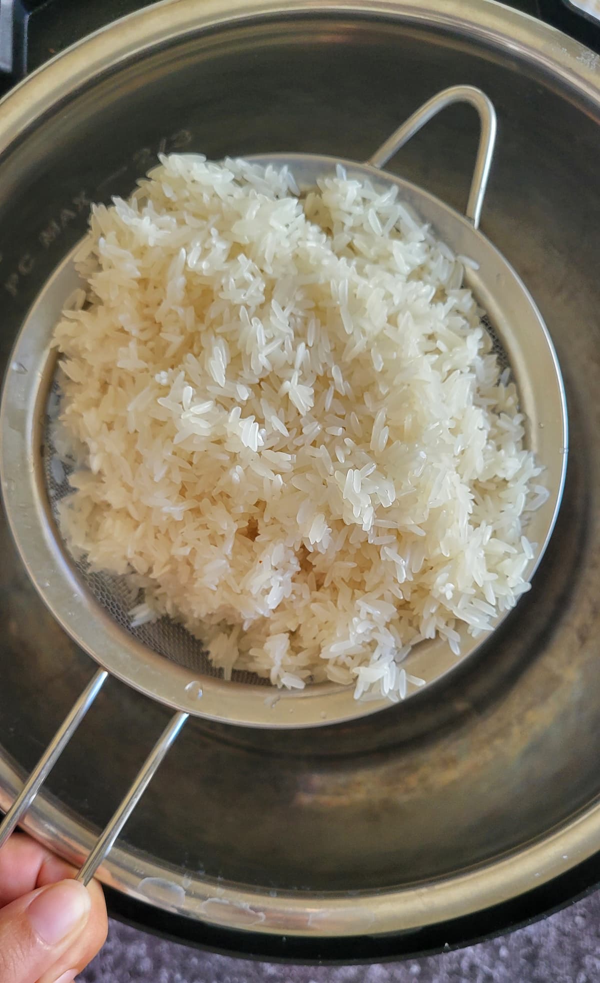 white rice in a strainer over a pot