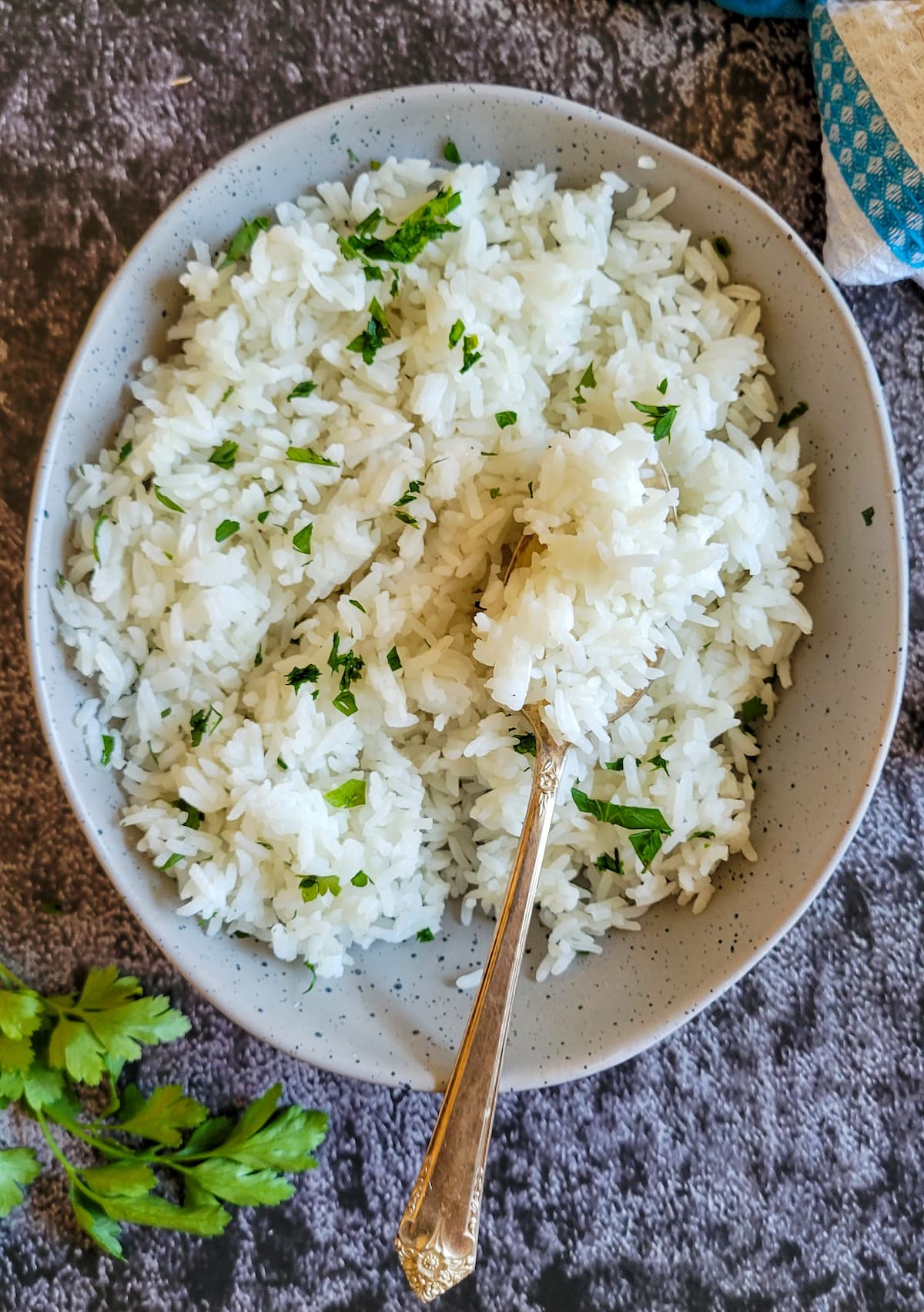 bowl of white rice garnished with fresh chopped parsley, spoon in the bowl
