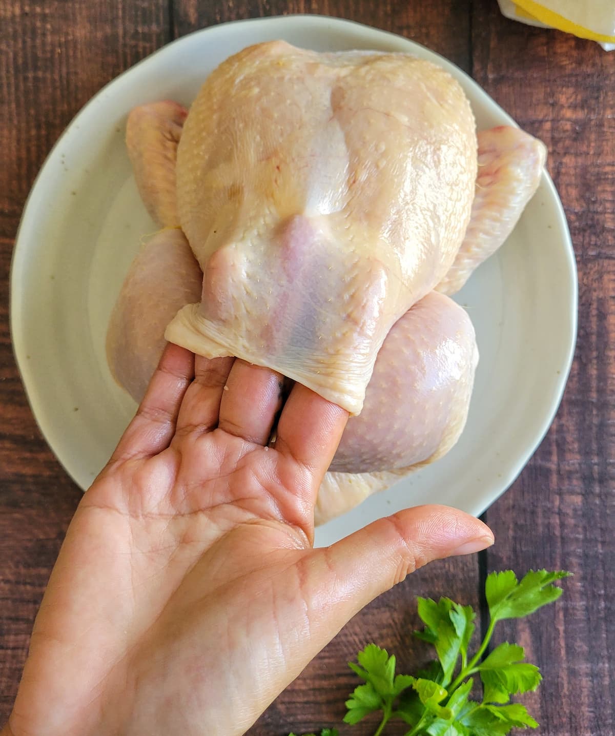 hand with 4 fingers under the skin of a whole chicken