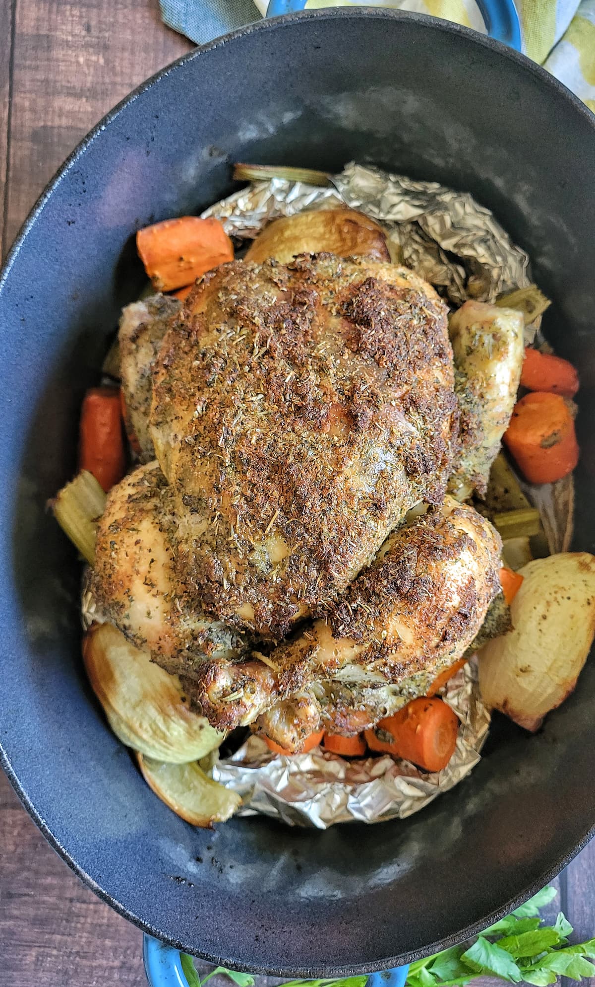 whole roasted chicken in a dutch oven with carrots and onions