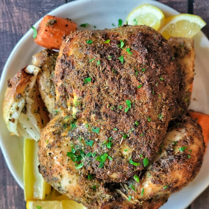a whole roasted chicken with lemon, herbs, onions and carrots