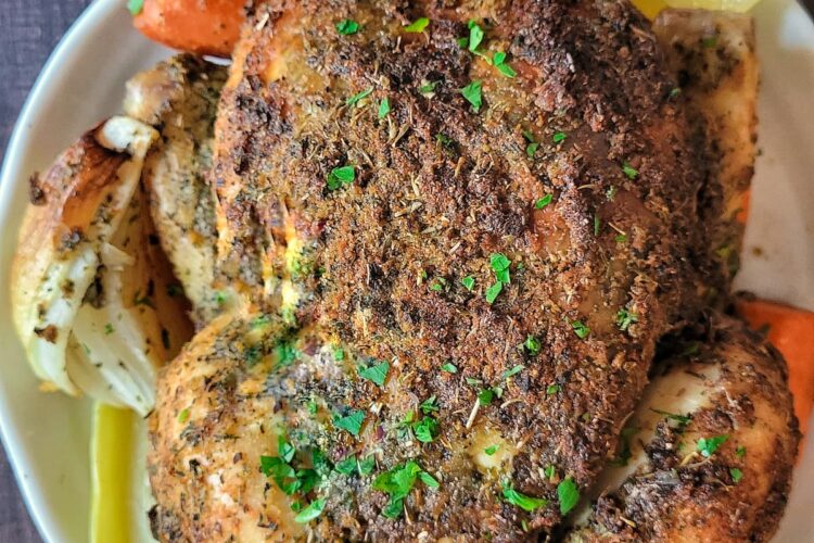 a whole roasted chicken with lemon, herbs, onions and carrots