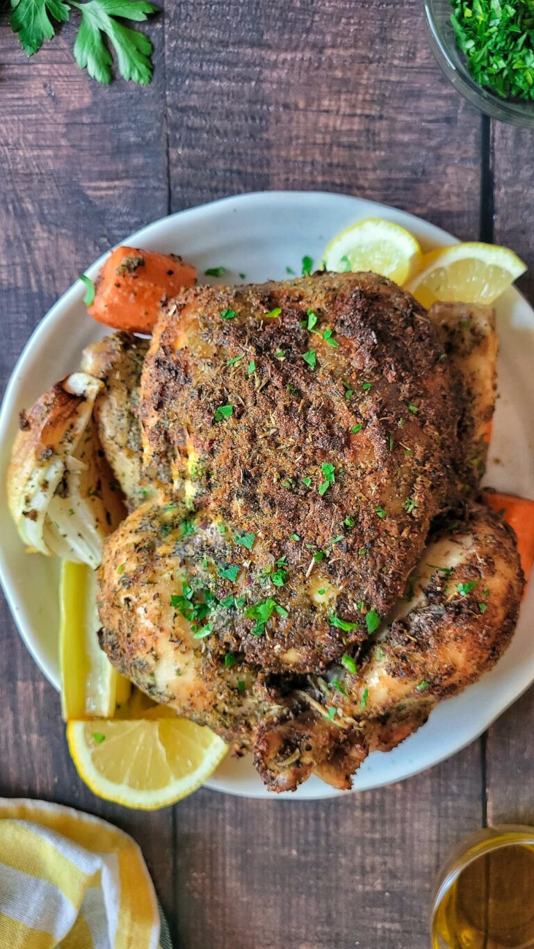 a whole roasted chicken with lemon, herbs, onions and carrots